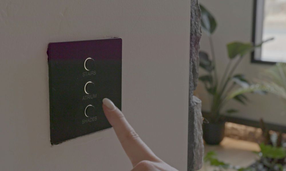A hand tapping a smart lighting wall keypad.
